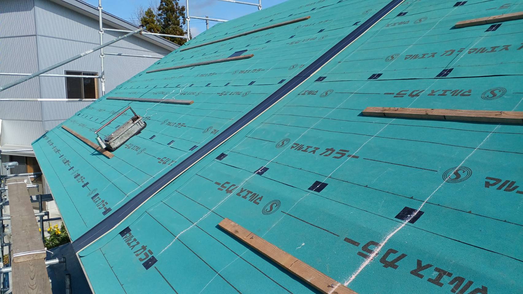 横葺きが長いので、作業効率・コストの面から横葺きジョイントを採用しています。<br />
ジョイントは自社製です。<br />
木材が見えますが、これは屋根の勾配が強いので足掛かりのためにつけています。